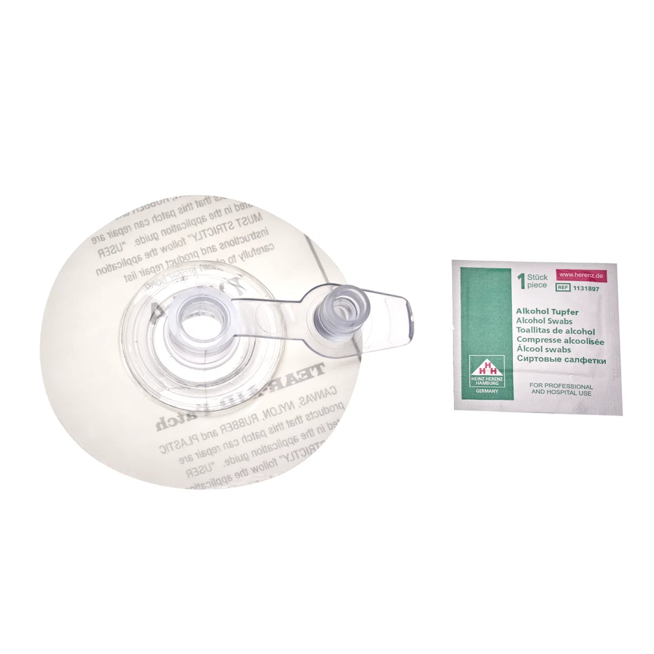 Round clear kite repair patch with a valve opening, next to an alcohol prep wipe packet, on a white background.