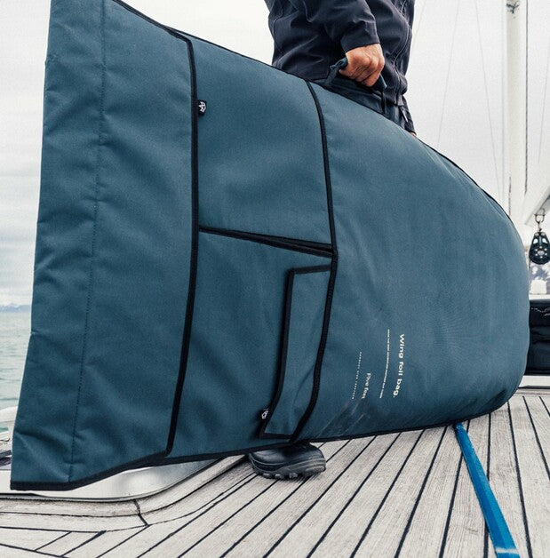 Person holding a large teal bag on a wooden deck