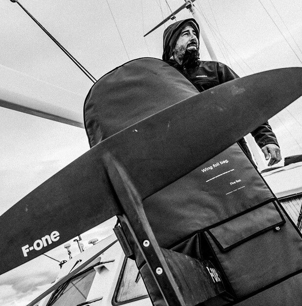 Person holding a F-one sailboard inside a sailboat