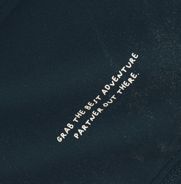 Close-up of a dark navy fabric surface with white embroidered text reading 'GRAB THE BEST ADVENTURE PARTNER OUT THERE.'